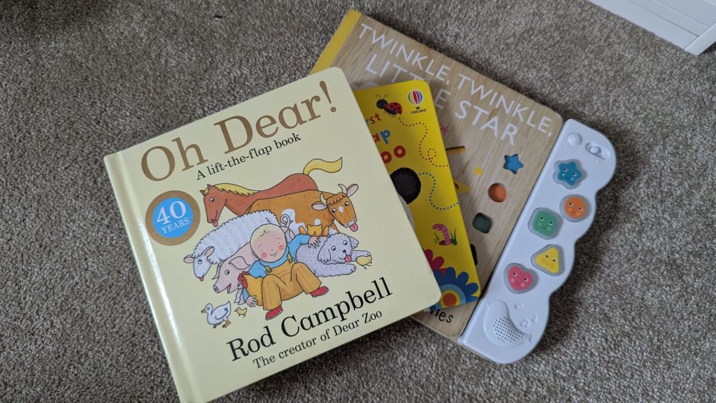 Three children's bedtime books stacked on a carpet including Oh Dear by Rod Campbell for a 10 month old bedtime routine.