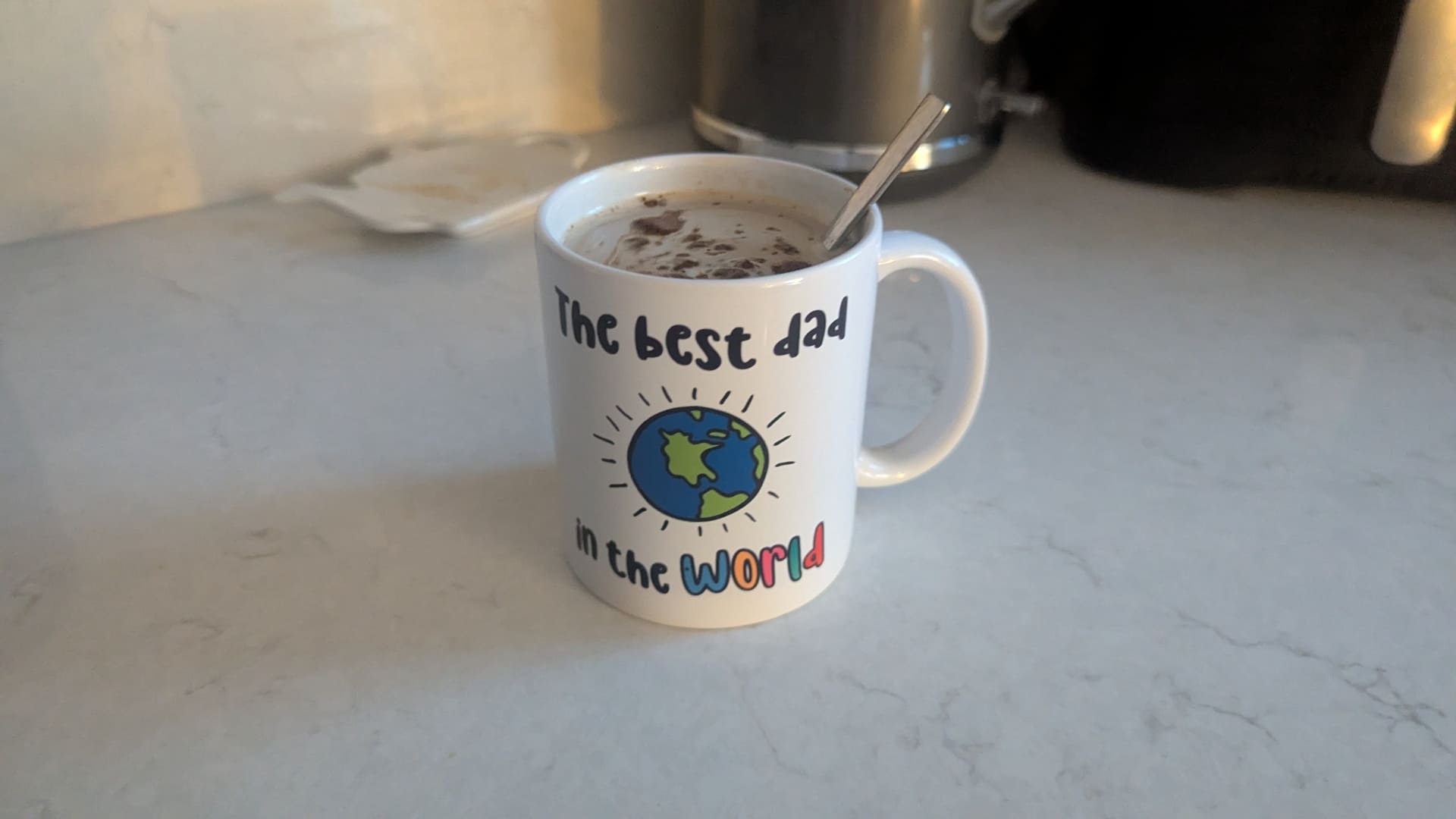A hot mug of coffee reading The best dad in the world sitting on a kitchen worktop during the 10 month sleep regression.