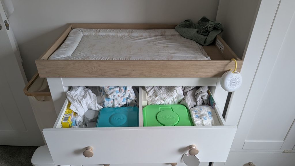 Wooden changing table with changing mat on top and open drawer below showing organised Cheeky Wipes tubs.