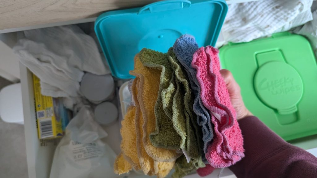 Hand holding a thick stack of colorful rainbow Cheeky Wipes cloth wipes showing material density and soft texture.