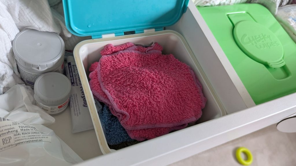Open blue Cheeky Wipes fresh container filled with damp colourful cloth wipes ready to use.