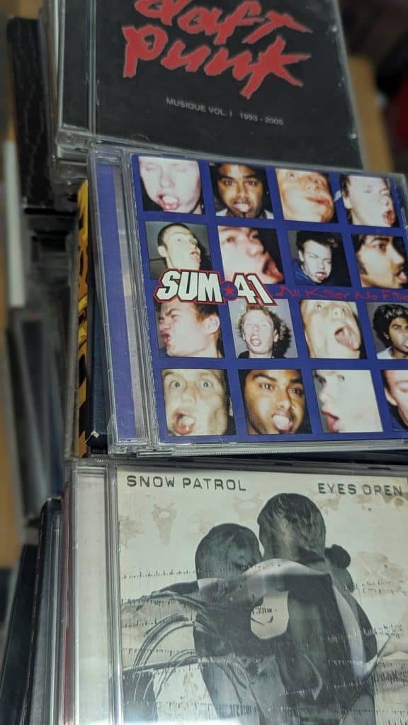 Close-up of music CD jewel cases featuring Sum 41 All Killer No Filler, Snow Patrol Eyes Open, and Daft Punk.