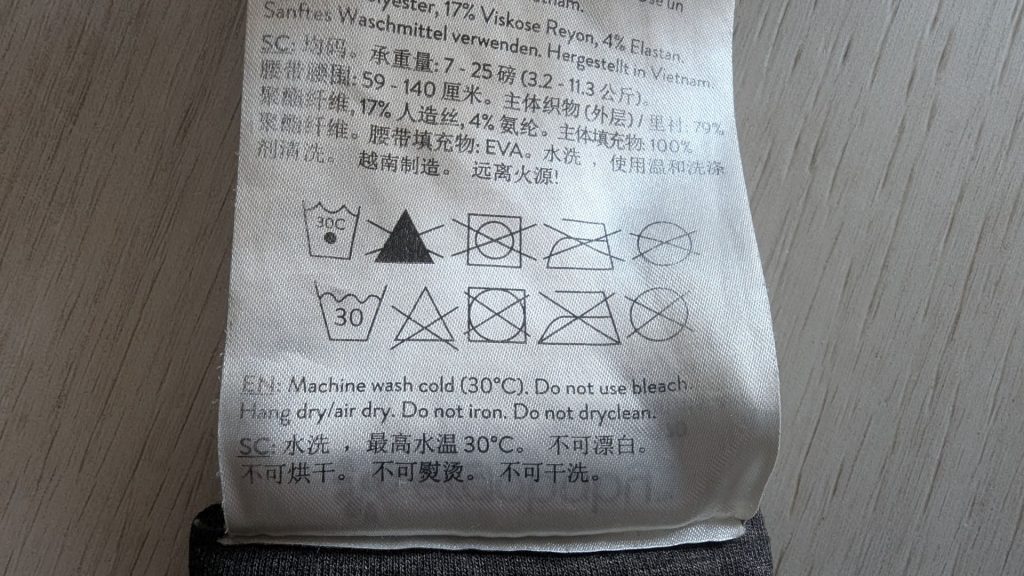 Close-up of the official Ergobaby care label showing 30°C machine wash symbols and fabric composition details.