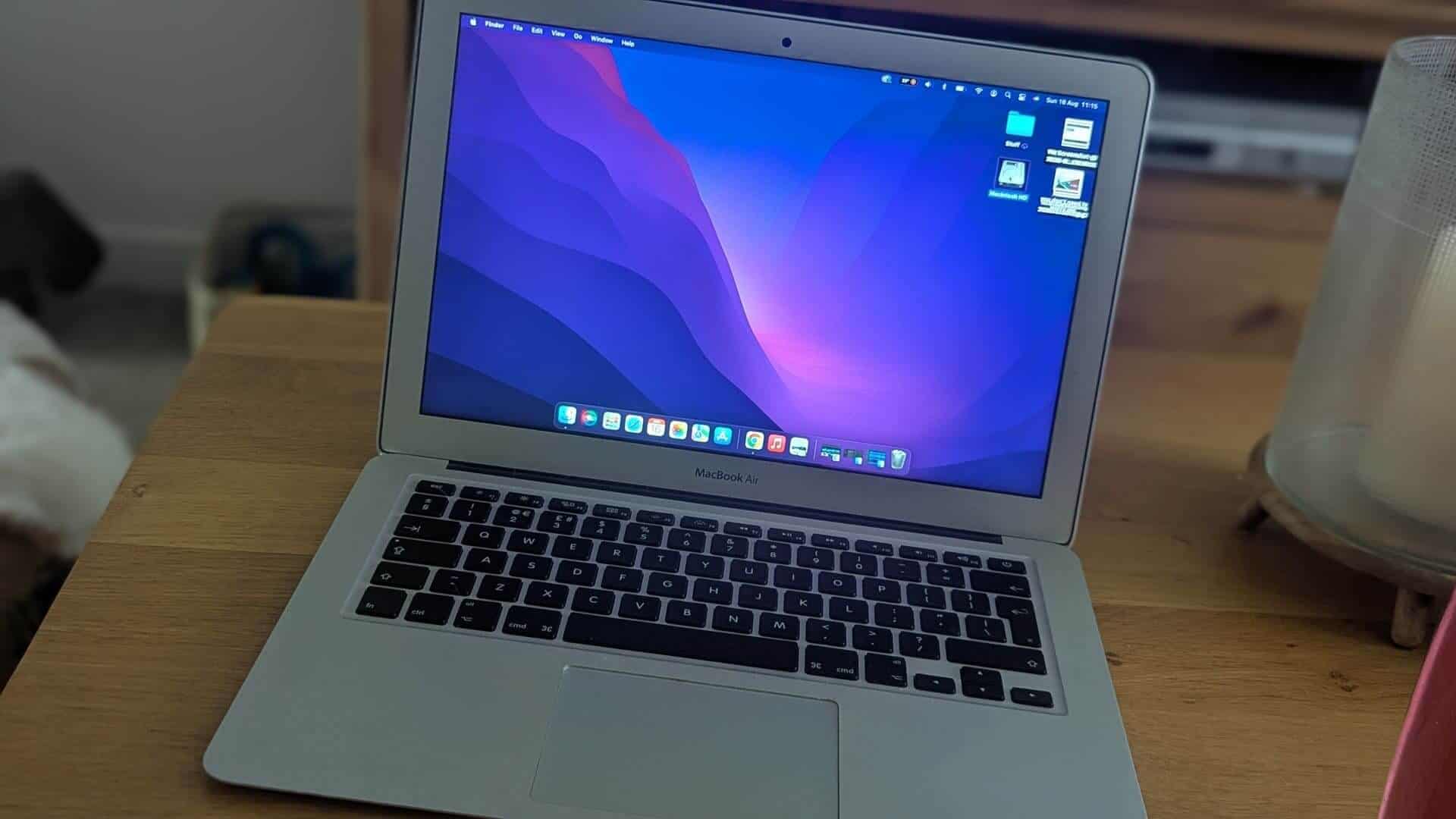Open silver MacBook Air laptop sitting on a wooden table with the macOS desktop active.