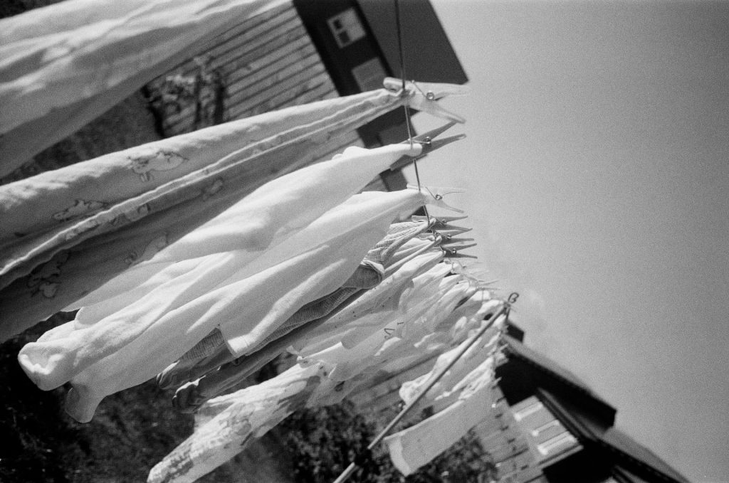 Paternity Leave for Dads: Black and white film photo of baby muslins and clothes pinned along a washing line outside.