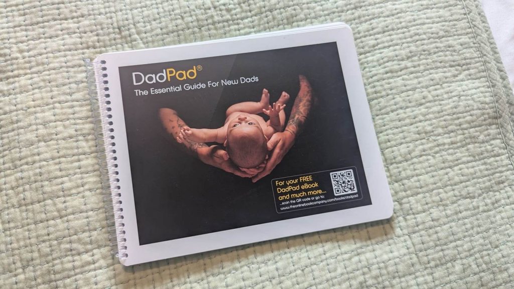 Ring-bound copy of The DadPad book lying flat on a green textured blanket.