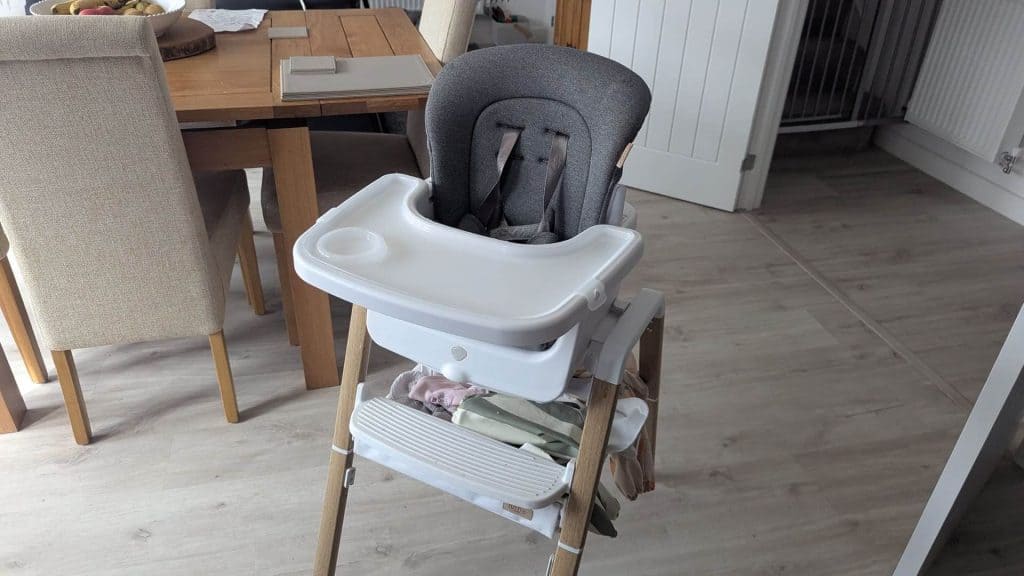 Close-up of the Tutti Bambini Nova Highchair showing the under-seat storage shelf filled with bibs and wipes.