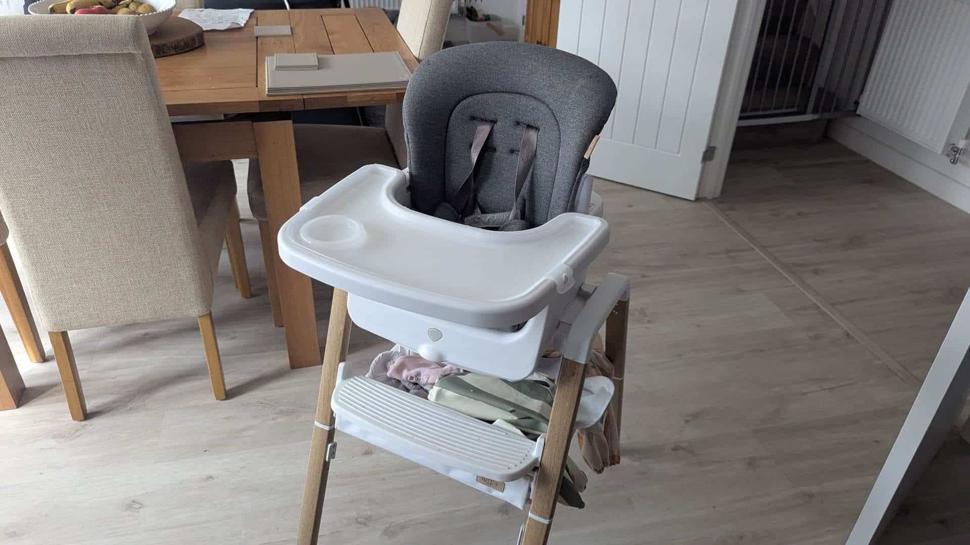 Close-up of the Tutti Bambini Nova Highchair showing the under-seat storage shelf filled with bibs and wipes.