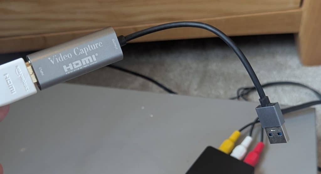 The complete signal chain showing the upscaler connected via HDMI to a silver USB video capture card on top of the VCR.