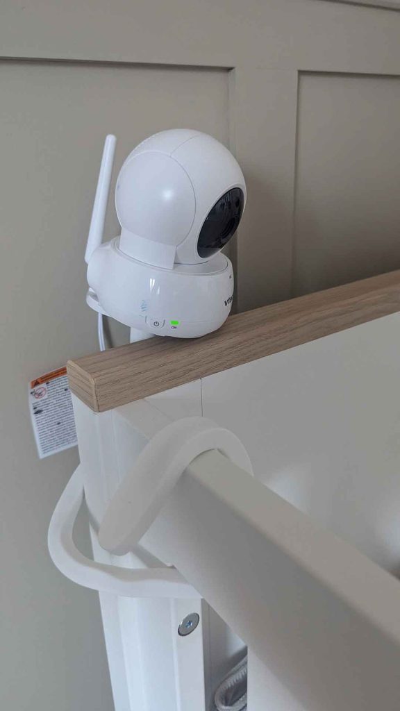 VTech baby monitor camera mounted to white wooden cot rail using a separate flexible twist mount bracket