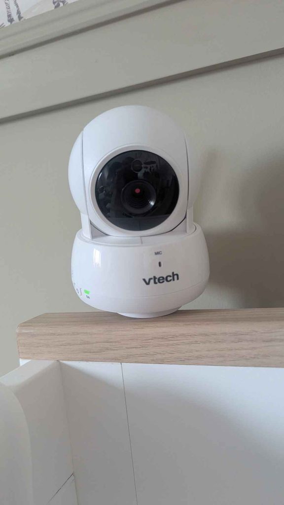 Front view of white VTech video baby monitor camera unit with infrared lens perched on cot rail