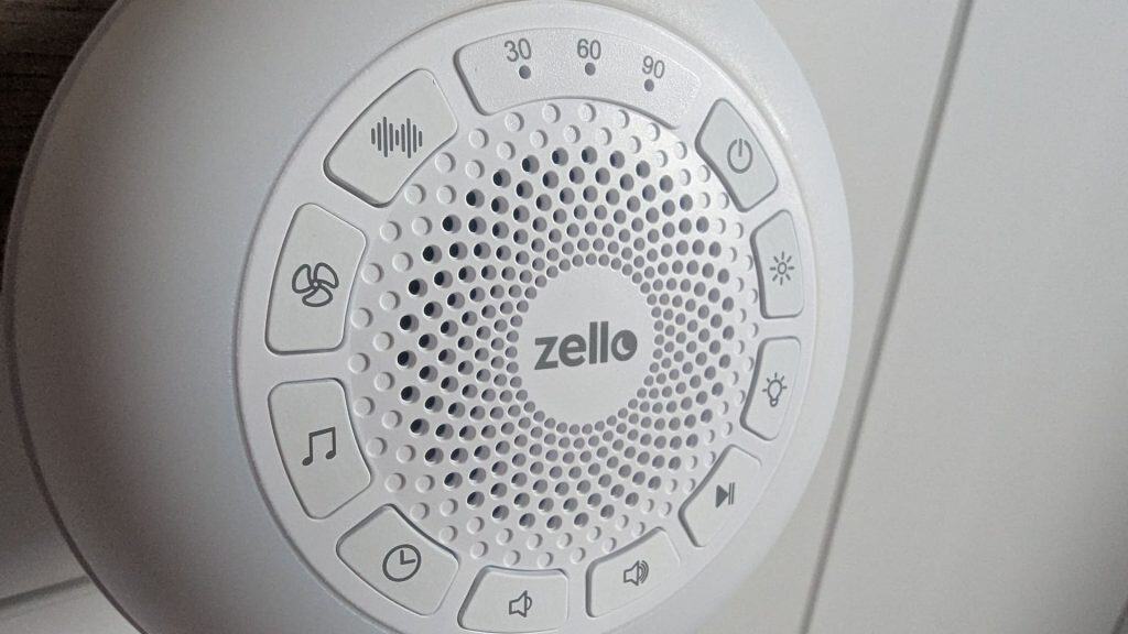Macro shot of the Zello white noise machine control panel showcasing button layouts, speaker grill, and brand logo.