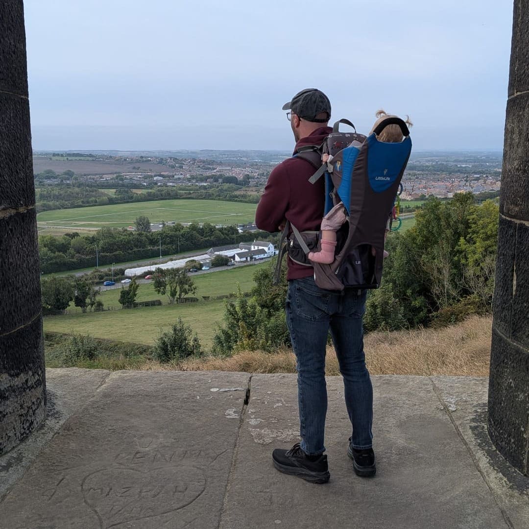 Dad standing at Penshaw Monument looking out at the Sunderland countryside view carrying an 11 month old baby in a Littlelife back carrier.