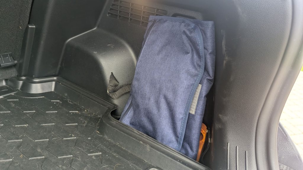 Dark blue travel changing kit tucked securely in the side storage compartment of a Hyundai Bayon boot next to a torch.