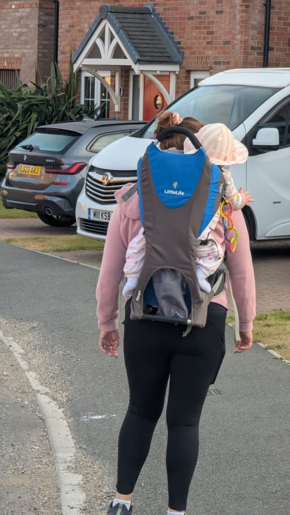 Close-up rear view of Mam carrying a baby wearing a sun hat in a Littlelife Ranger child carrier review setup.