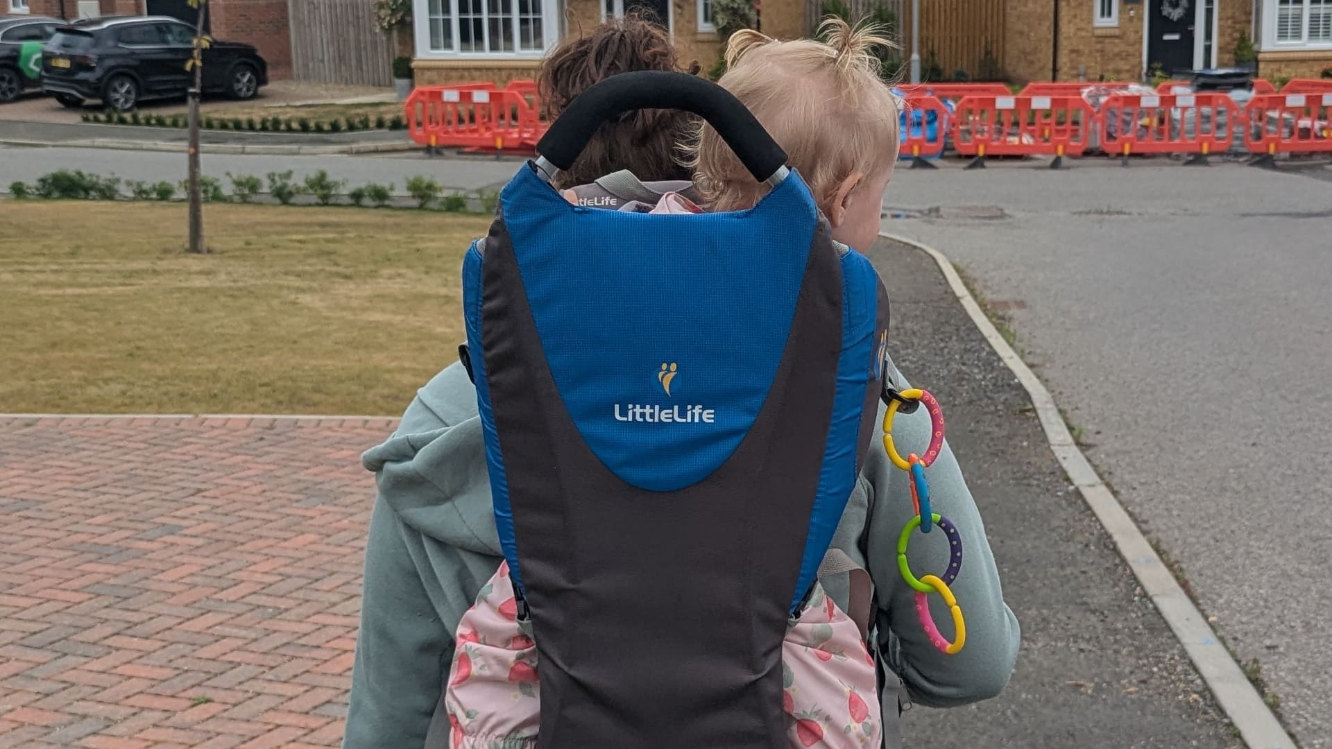 Mam carrying baby in a blue Littlelife Ranger child carrier review testing model during a neighbourhood walk.